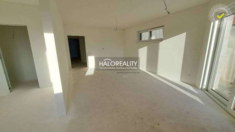 Interiér s bílými stěnami a okny v rodinném domě, připravený k dokončení.