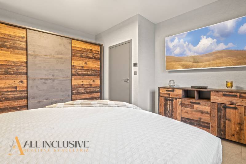 Ložnice v rodinném domě s nábytkem a skříní s dekorem přírodního dřeva.