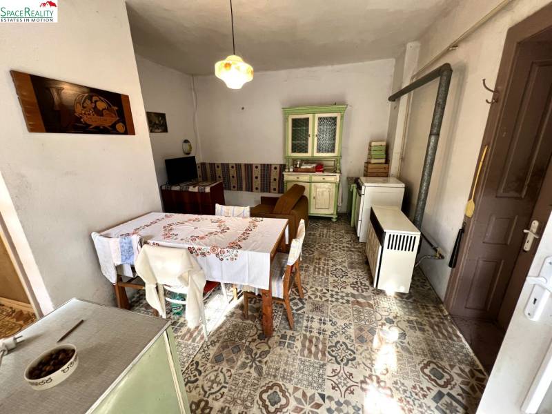 Tradiční kuchyně v rodinném domě s vintage nábytkem a zdobenou podlahou s dekorem.