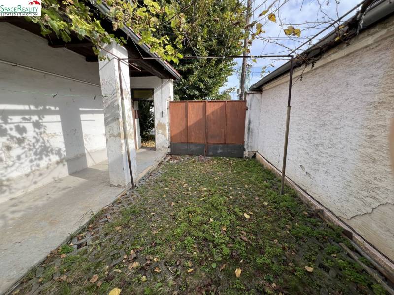 Dvůr rodinného domu v Jablonci s kamennou dlažbou a zelení.
