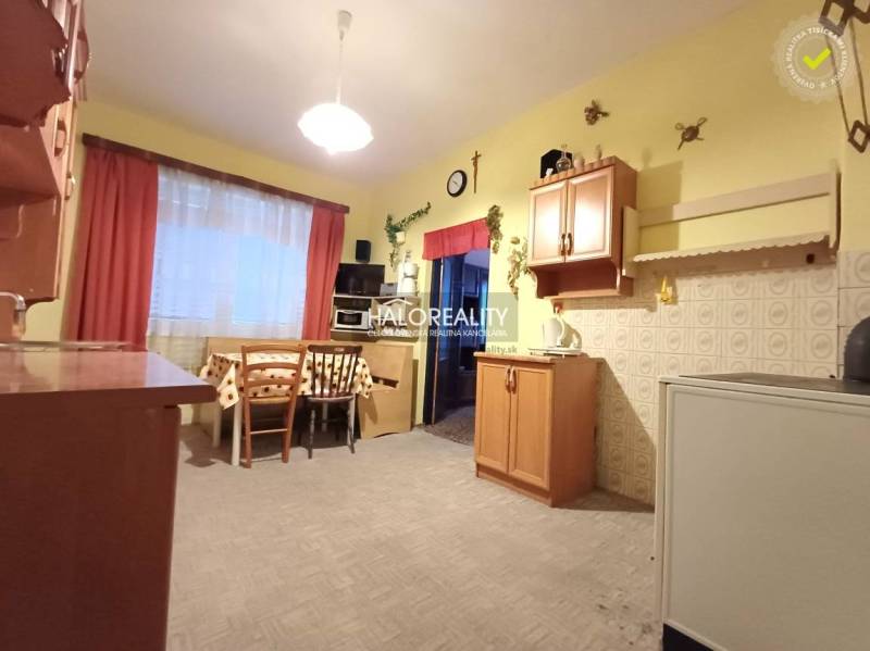 Kuchyně v rodinném domě s dřevěným dekorem, světlé stěny, stůl se židlemi.