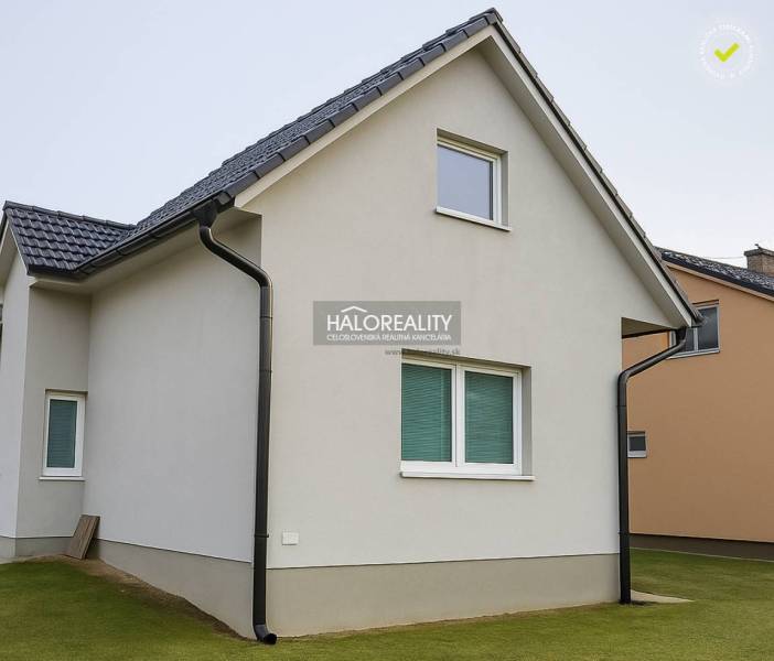 Rodinný dům v Kľačne s bílou fasádou a šikmou střechou na udržovaném trávníku.