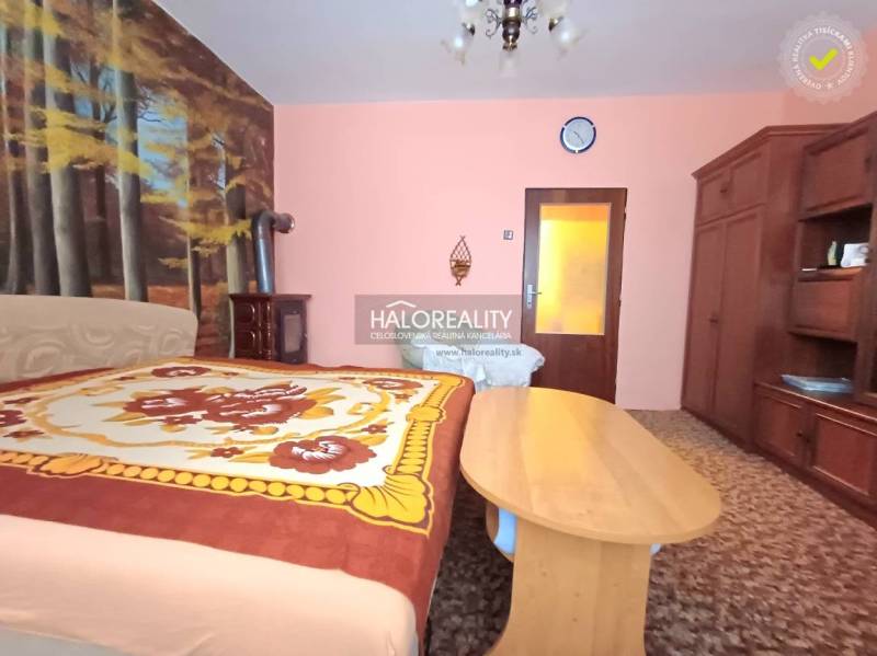 Ložnice v rodinném domě s tapetou lesa a klasickým dřevěným nábytkem.