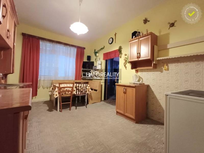 Kuchyně v rodinném domě s dřevěným dekorem, jídelním stolem a skříňkami.