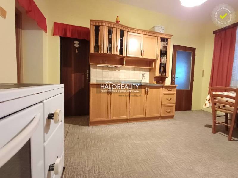 Kuchyně v rodinném domě s dřevěnými skříňkami a klasickým sporákem.