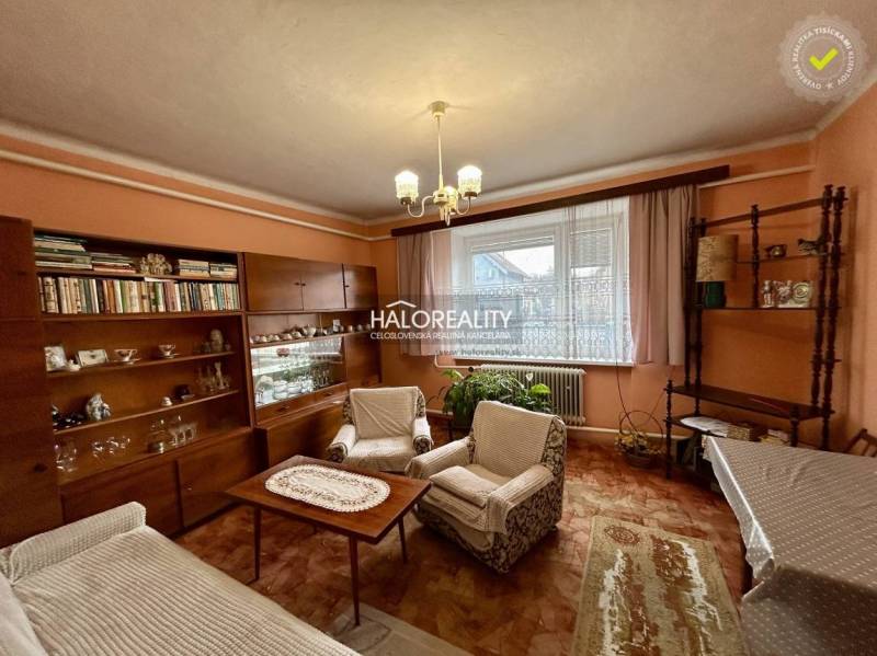 Obývací pokoj rodinného domu s nábytkem s dřevěným dekorem a záclonami.