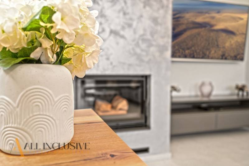 Váza s květinami na stole, podlaha s dřevěným dekorem, krb v rodinném domě.