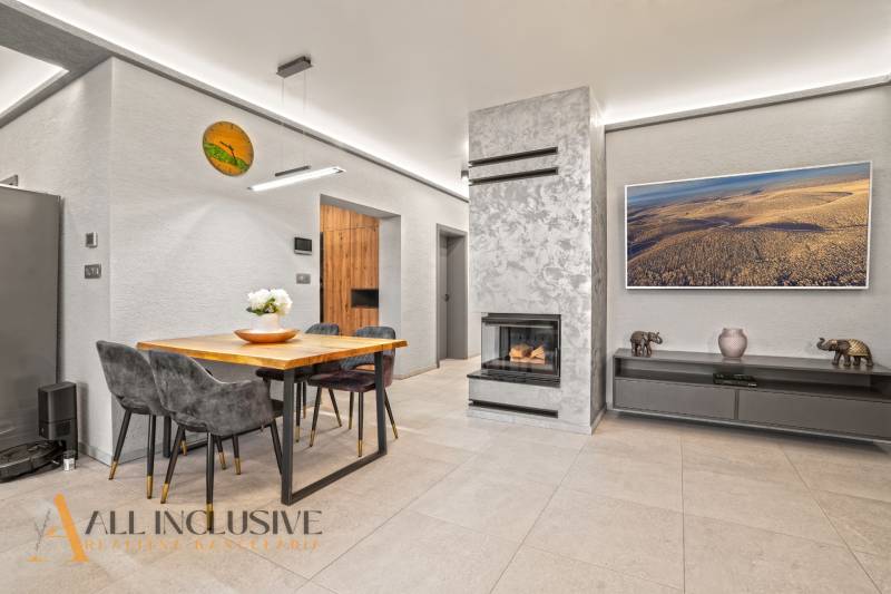 Obývací pokoj v rodinném domě s krbem, stolem pro čtyři a dekoracemi.