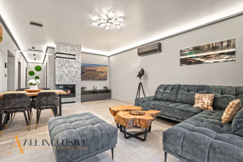 Interiér rodinného domu s pohodlnou sedačkou, krbem a stolem z dřevěného dekoru.