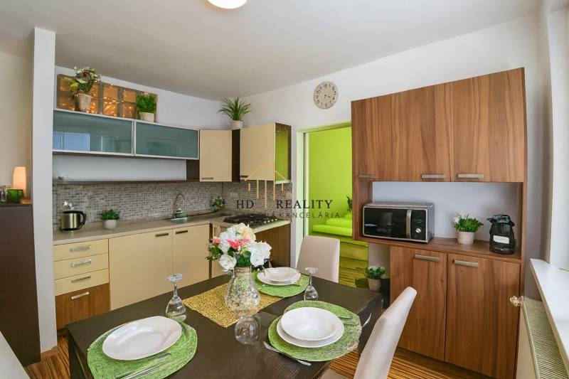 Kuchyně v 1-pokojovém bytě s jídelním stolem a podlahou s dřevěným dekorem.