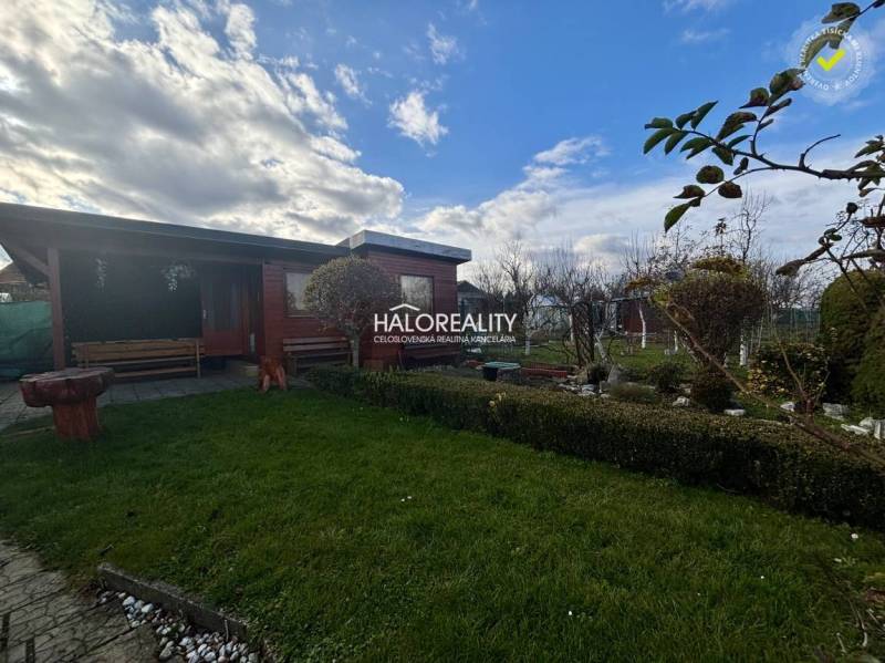 Dřevěný altán v zahradě ve Spišské Nové Vsi se zeleným trávníkem a zelení.