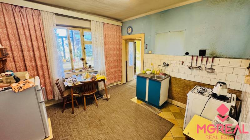 Kuchyně v rodinném domě s jídelním stolem, plynový sporák a dřez.