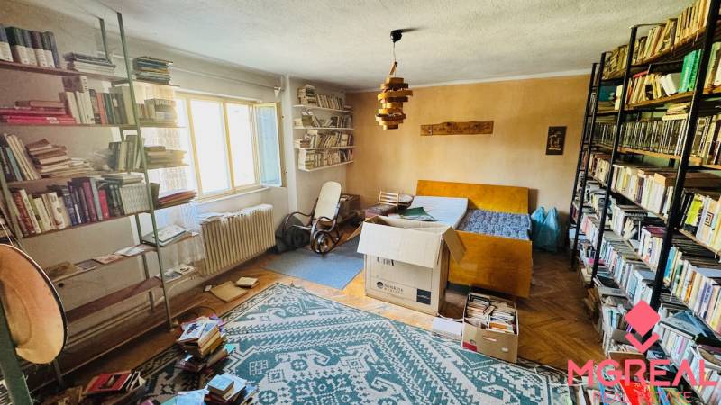 Knihovna a nábytek v pokoji rodinného domu s podlahou s dřevěným dekorem.