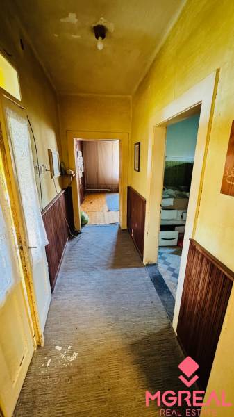 Chodba s kobercem a dřevěným obložením v rodinném domě, místnost vpravo.