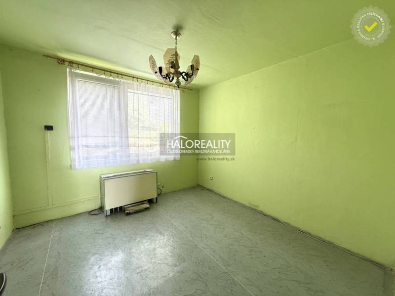 Pokoj s lustrem, oknem a topným tělesem v 3-pokojovém bytě.