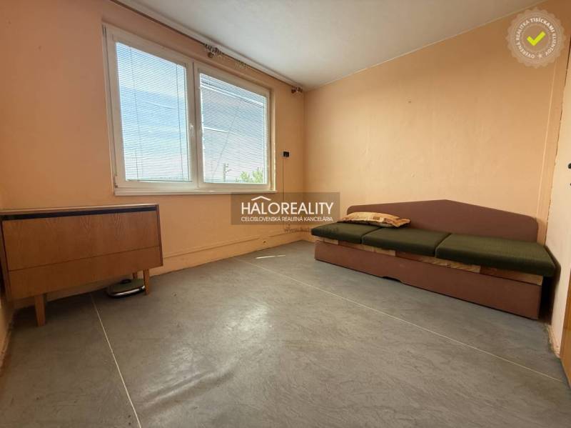 Světlý pokoj s pohovkou v 3-pokojovém bytě, dřevěný nábytek, velké okno.