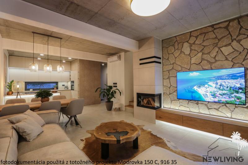 Obývací pokoj v rodinném domě s krbem, TV na kamenné stěně a podlahou s dřevěným dekorem.