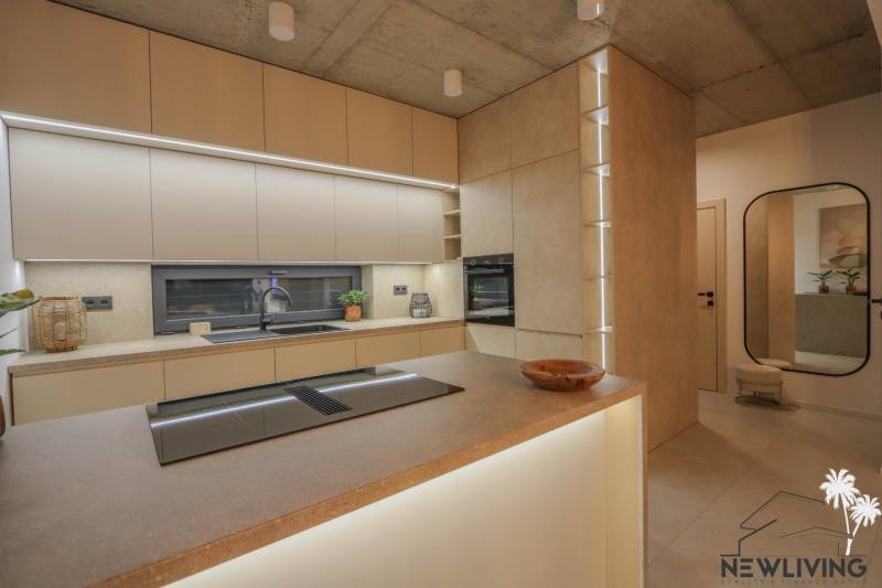 Kuchyně v rodinném domě se zabudovanými spotřebiči, pracovními deskami a podlahou s dřevěným dekorem.