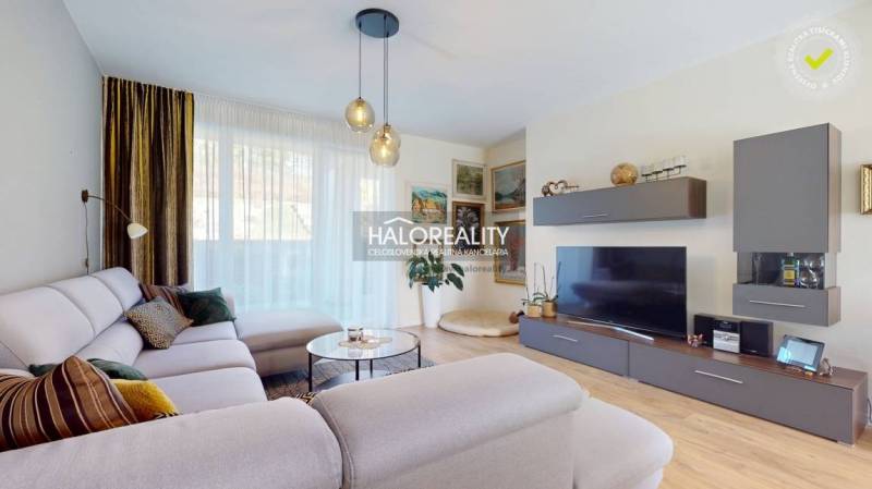 Obývací pokoj v rodinném domě s pohodlnou sedačkou a podlahou s dřevěným dekorem.