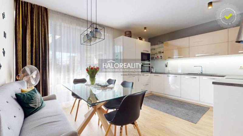 Kuchyně v rodinném domě s jídelním stolem, sedačkou a podlahou s dřevěným dekorem.