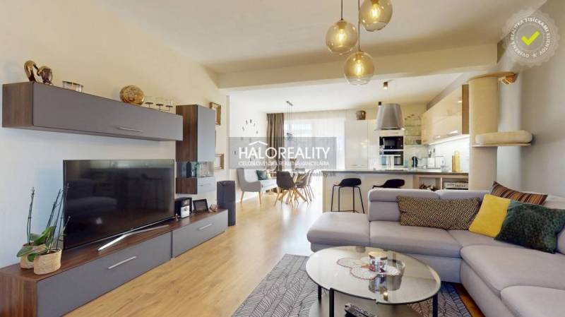 Obývací pokoj s podlahou s dřevěným dekorem, pohodlnou sedačkou a prostornou kuchyní v rodinném domě.