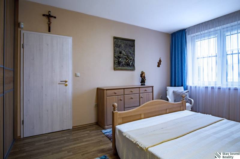 Ložnice s podlahou s dřevěným dekorem v rodinném domě, dřevěná postel a komoda.