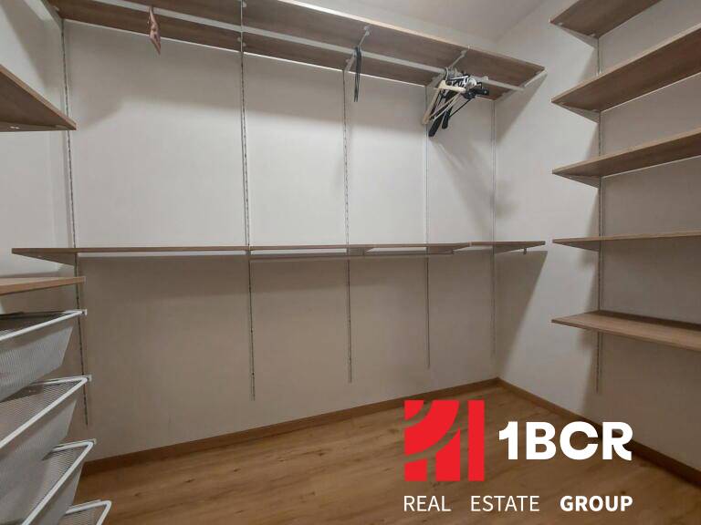 Šatník v 2-pokojovém bytě s poličkami a podlahou s dřevěným dekorem.