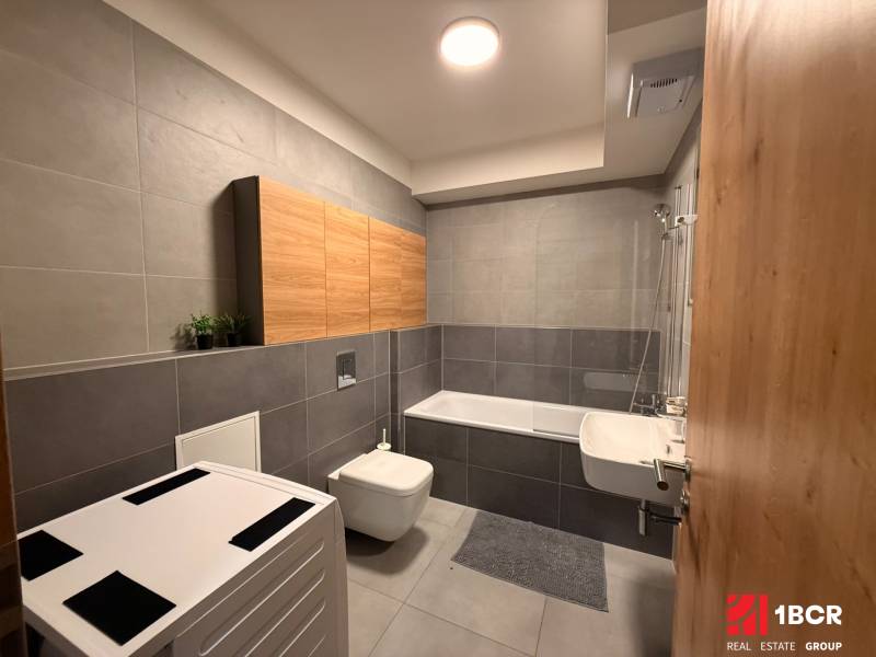 Koupelna v 2-pokojovém bytě s vanou, umyvadlem, závěsnou toaletou a skříňkami.