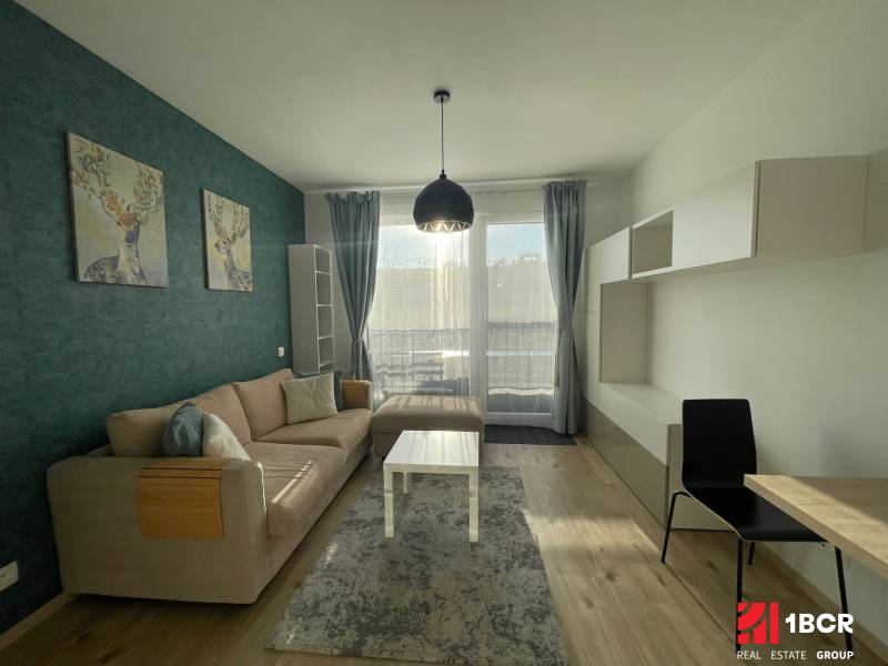 Obývací pokoj 1+kk s pohovkou, dekorací jelena a podlahou s dřevěným dekorem.