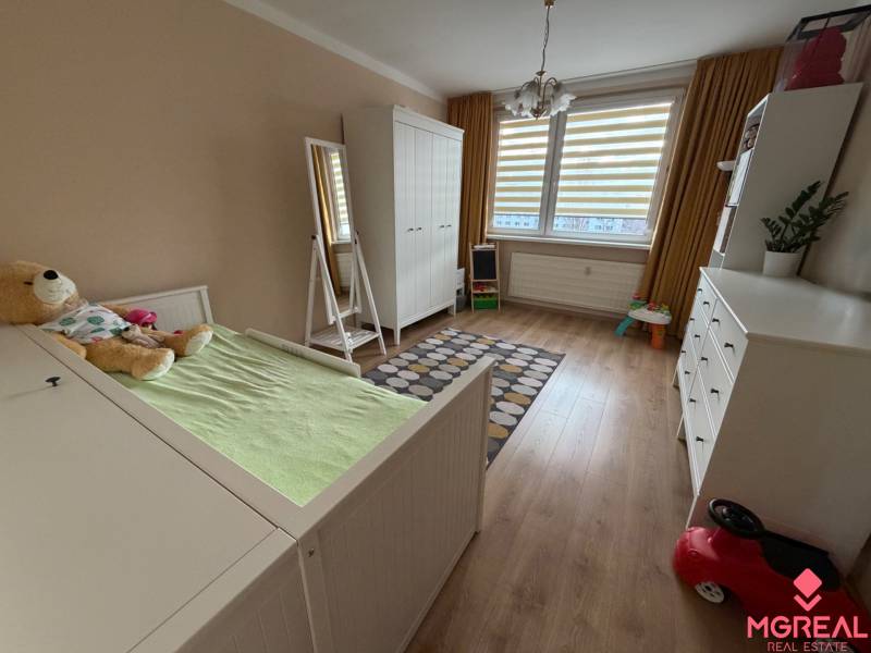 Dětský pokoj s podlahou s dřevěným dekorem ve 4-pokojovém bytě, s bílým nábytkem.