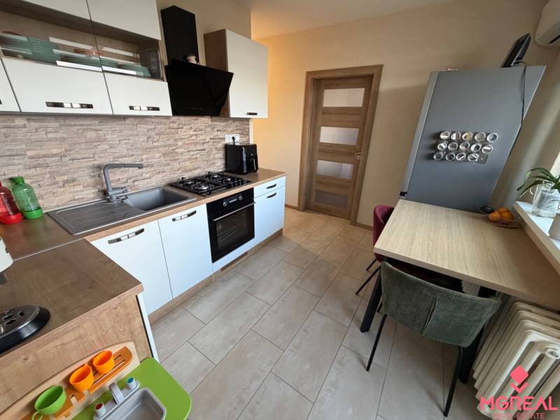 Kuchyně ve 4-pokojovém bytě s podlahou s dřevěným dekorem a vestavěnými spotřebiči.