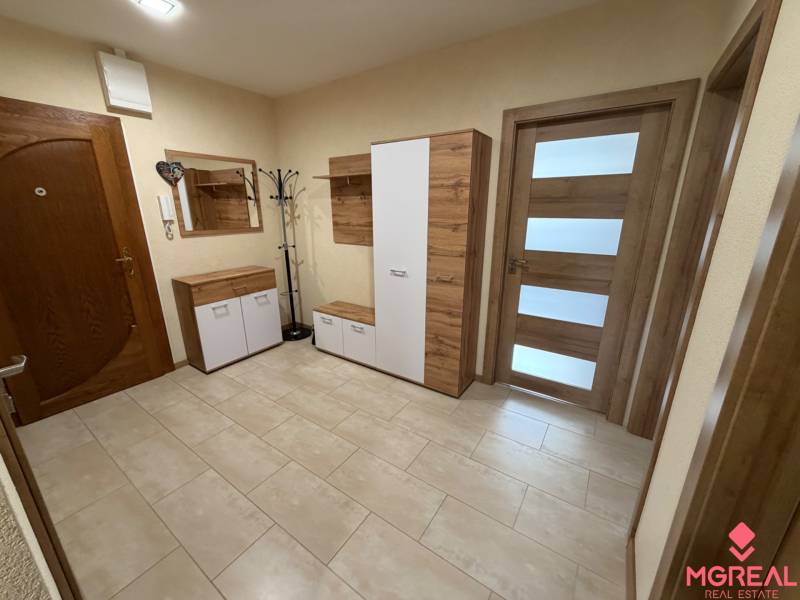 Vstupní hala s praktickým úložným nábytkem a světlou podlahou s dřevěným dekorem ve 4pokojovém bytě.