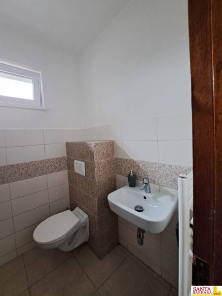 Toaleta ve 4pokojovém bytě s bílými a vzorovanými obklady.