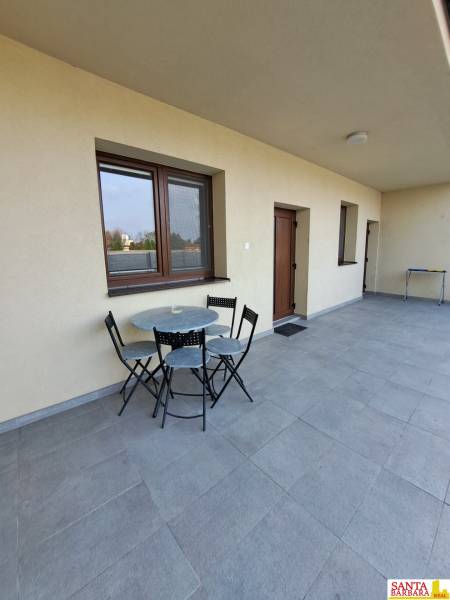 Terasa s posezením ve 4-pokojovém bytě s dlážděnou podlahou a světlými stěnami.