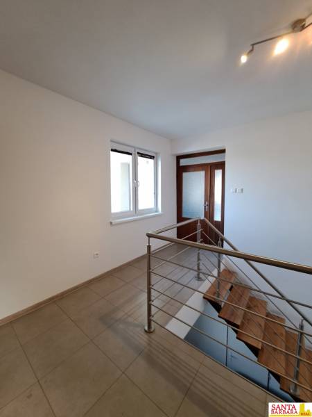 Chodba s keramickou dlažbou a schodištěm ve 4pokojovém bytě.