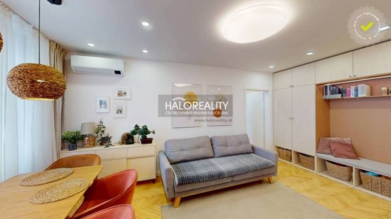 Obývací pokoj s pohovkou, jídelním stolem a podlahou s dřevěným dekorem ve 3pokojovém bytě.