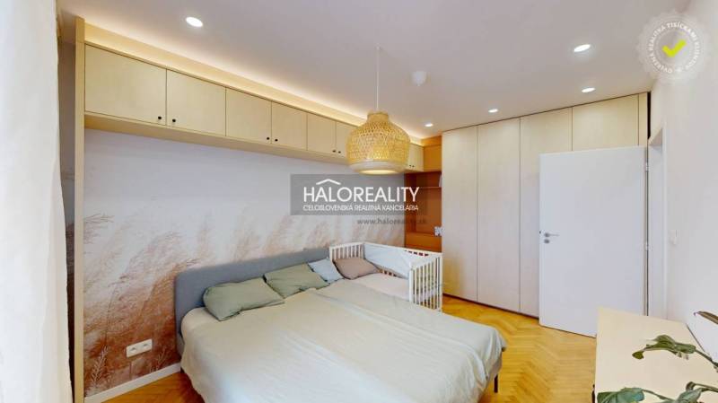 Ložnice v 3-pokojovém bytě s vestavěnými skříněmi, postelí a postýlkou.