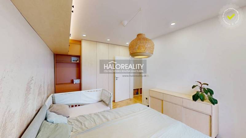 Dětský pokoj s postelí, ratanovou lampou a šatní skříní v 3-pokojovém bytě.