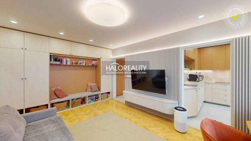 Obývací pokoj v 3-pokojovém bytě s podlahou s dřevěným dekorem a vestavěným úložným prostorem.