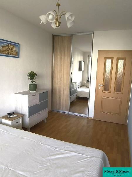 Ložnice v 2-pokojovém bytě s podlahou s dřevěným dekorem, vestavěnou skříní a komodou.