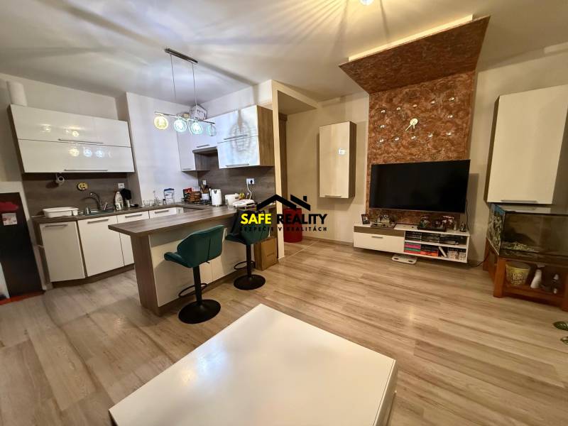 Obývací pokoj s kuchyní, barovým pultem a podlahou s dřevěným dekorem v 2pokojovém bytě.