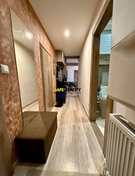 Chodba v 2-pokojovém bytě s podlahou s dřevěným dekorem, zrcadlem a botníkem.