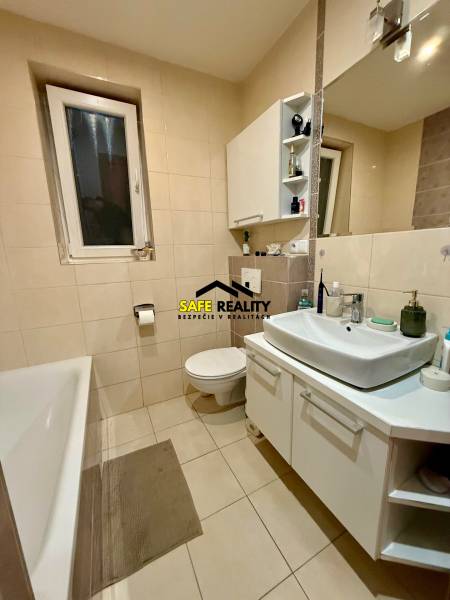 Koupelna s vanou a bílým umyvadlem v 2-pokojovém bytě.