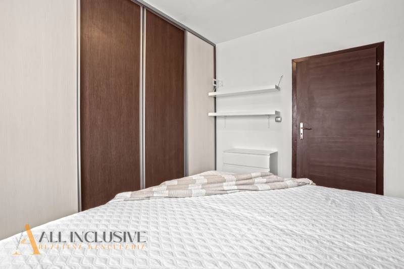 Ložnice v 3pokojovém bytě s postelí, vestavěnou skříní a minimalistickými policemi.