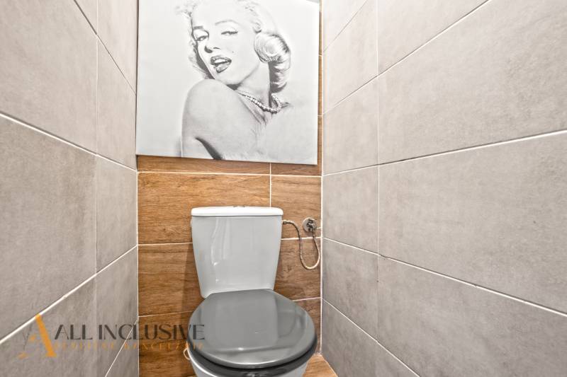 Toaleta v 3-pokojovém bytě s podlahou s dřevěným dekorem a nástěnnou fotografií.