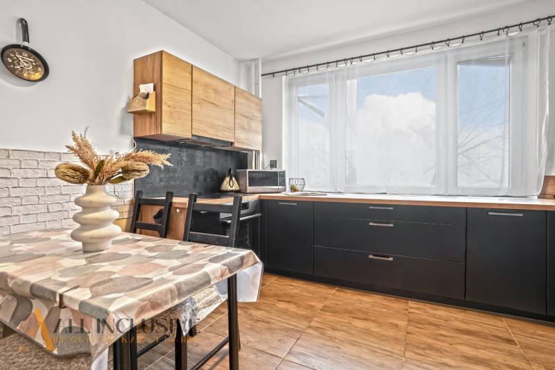 Kuchyně v 3-pokojovém bytě se světlou výzdobou a podlahou s dřevěným dekorem.