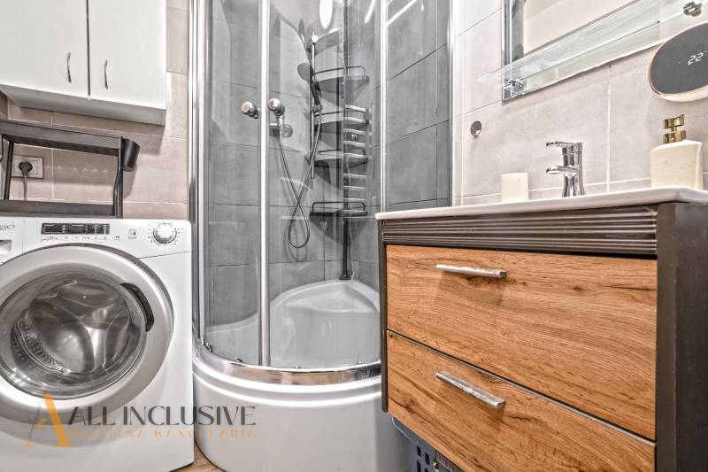 Koupelna s pračkou, sprchovým koutem a skříňkou v 3pokojovém bytě.