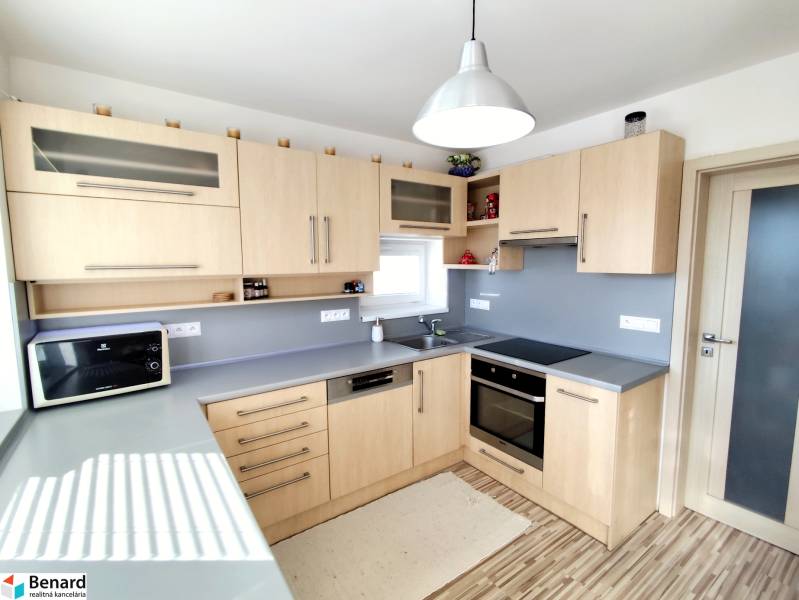 Kuchyně v rodinném domě s dřevěným dekorem a šedou pracovní deskou.