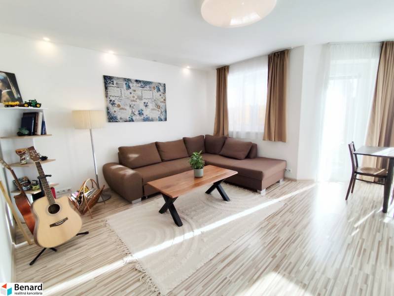 Obývací pokoj v rodinném domě s velkou sedačkou a podlahou s dřevěným dekorem.