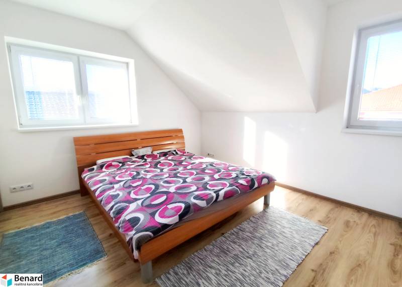 Ložnice s postelí a podlahou s dřevěným dekorem v rodinném domě.